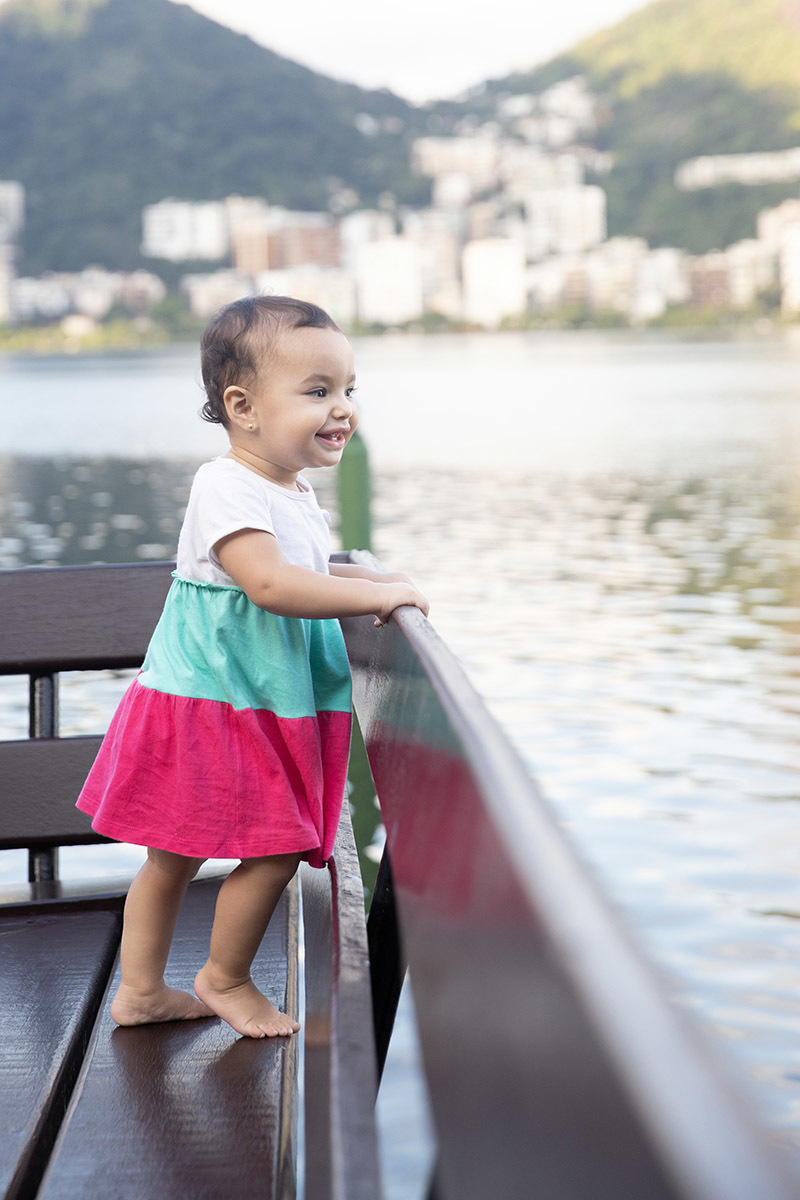 Ensaio de Família no Clube Piraquê: Laura no banco olhando para a Lagoa, no Rio de Janeiro.