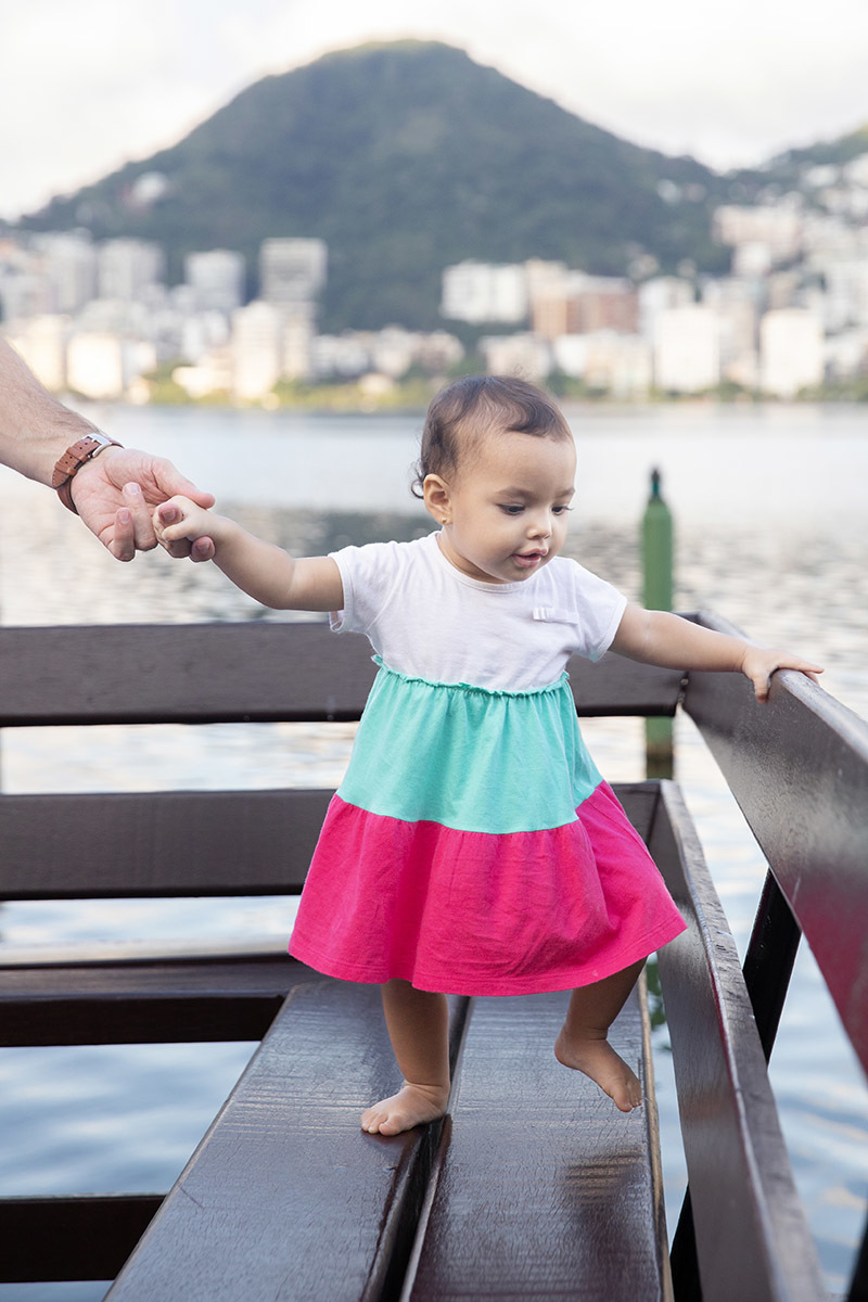 Ensaio de Família no Clube Piraquê: Laura no banco olhando para a Lagoa, no Rio de Janeiro.