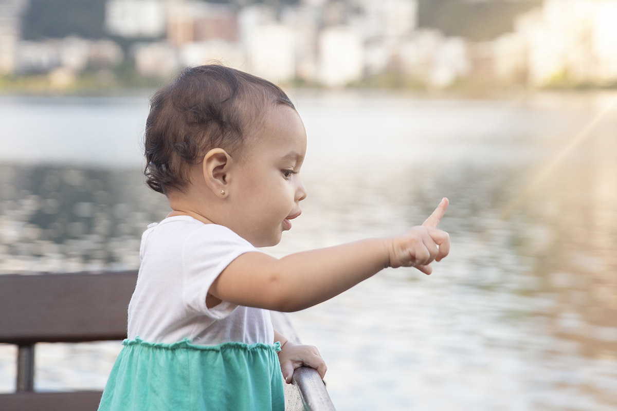 Ensaio de Família no Clube Piraquê: Laura no banco olhando para a Lagoa, no Rio de Janeiro.