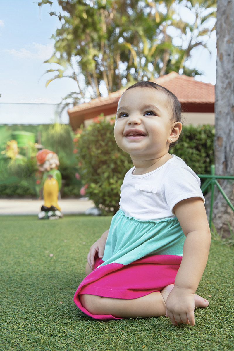 Ensaio de Família no Clube Piraquê: Laura sorrindo na grama, no Rio de Janeiro.