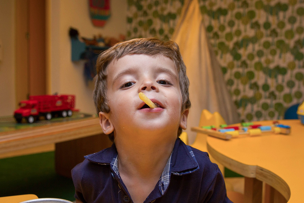 Festa de aniversário do Mateus: Mateus, 3 anos, comendo batata frita - Rio de Janeiro.