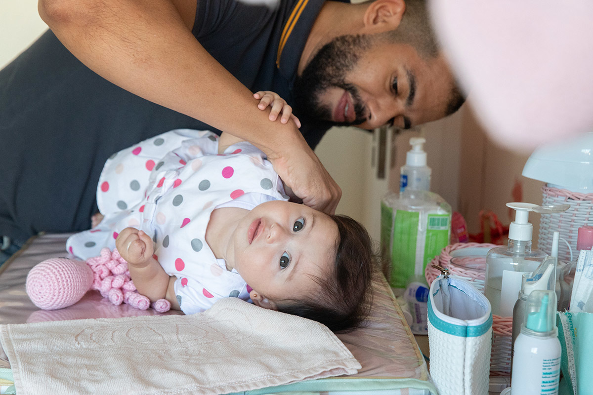 Igor colocando o vestido na bebê Maitê - ensaio de bebê - Rio de Janeiro - RJ.. 