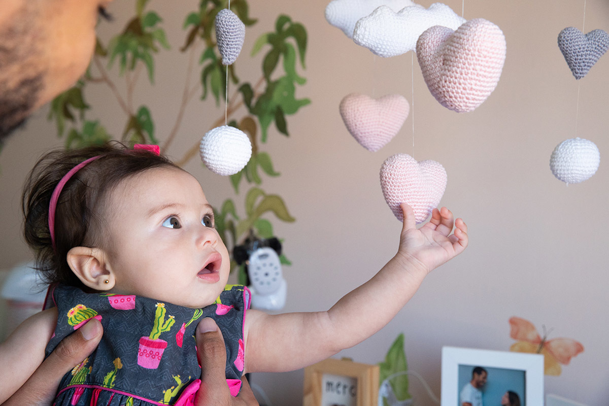 Maitê no colo do pai brincando com o móbile - ensaio de bebê - Rio de Janeiro - RJ. 