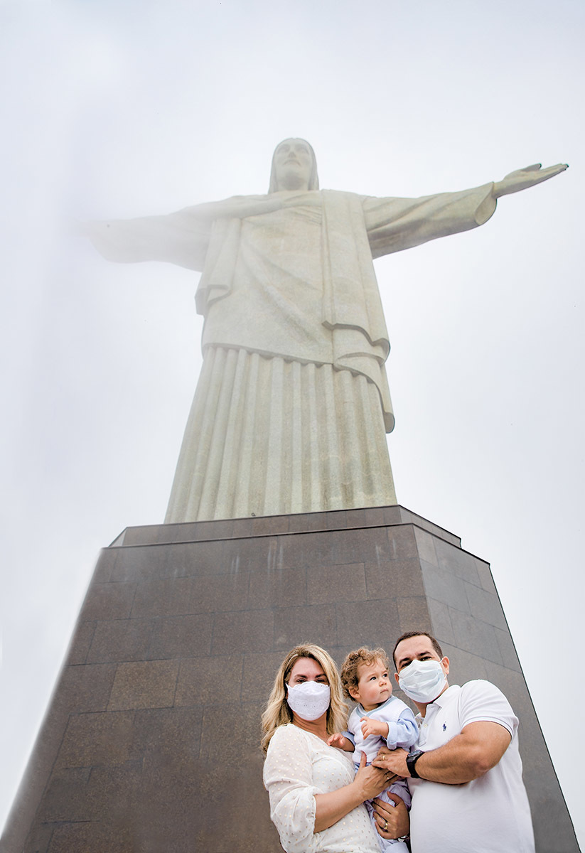 Batizado do Vitor: Mãe e pai levantando o Vitor em direção ao Cristo Redentor no Corcovado, no Rio de Janeiro.