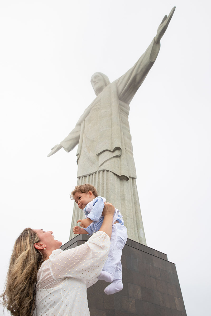 Batizado do Vitor: Mãe levantando o Vitor em direção ao Cristo Redentor no Corcovado, no Rio de Janeiro.