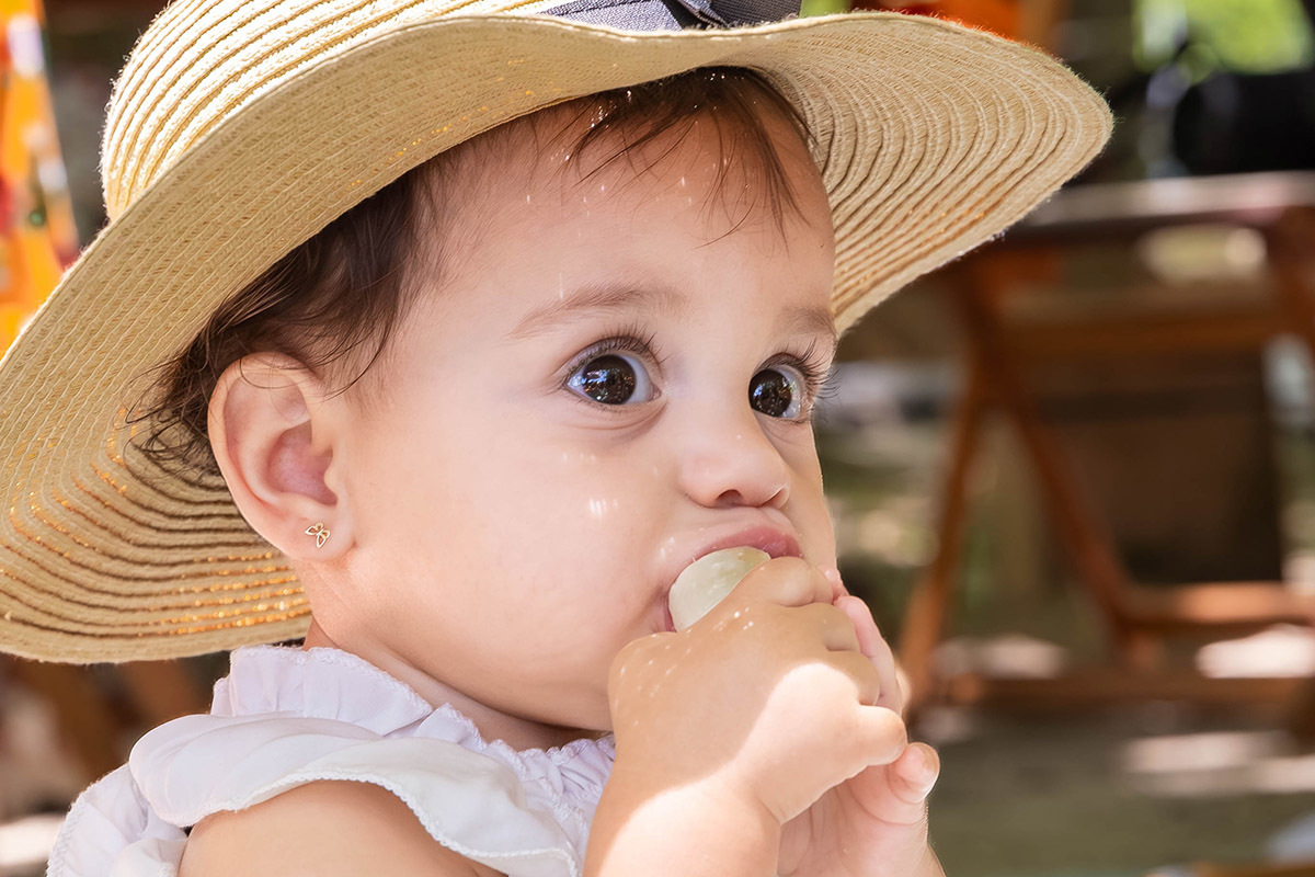 Alice de chapéu de palha comendo banana em sua festa Piquenique na lagoa no Rio de Janeiro