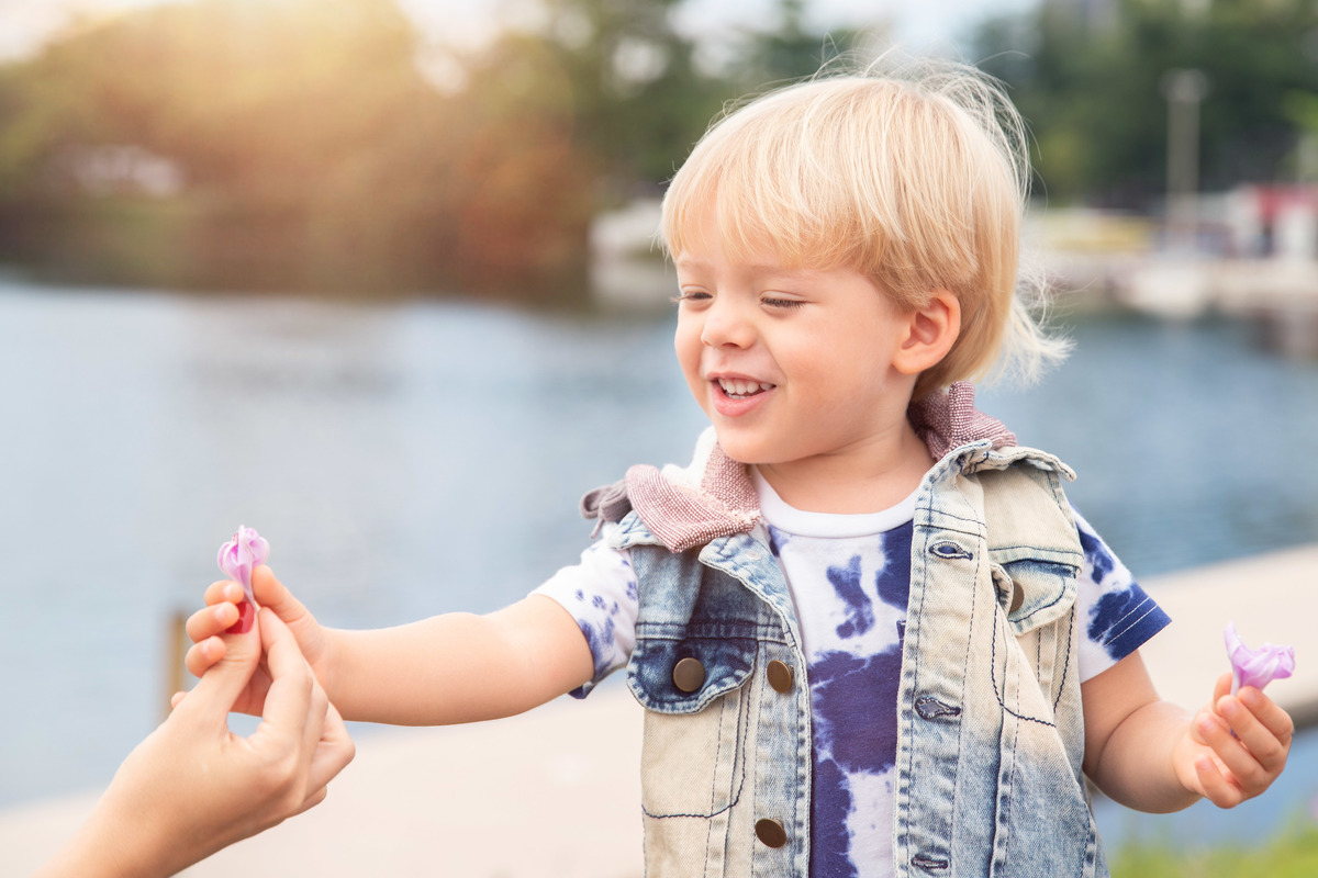Criança sorrindo entregando flor para a mãe durante ensaio fotográfico na Lagoa