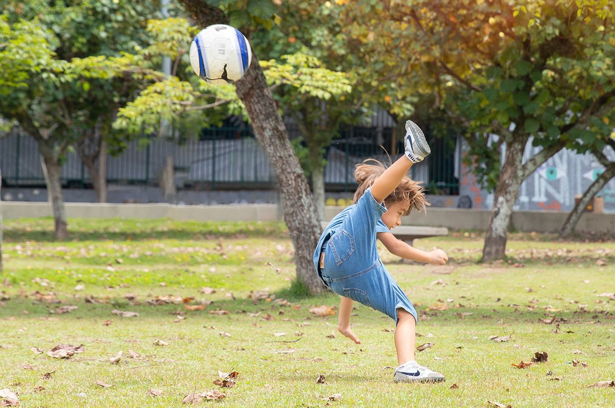 Menino chutando bola em ensaio infantil ao ar livre na Lagoa Rodrigo de Freitas

