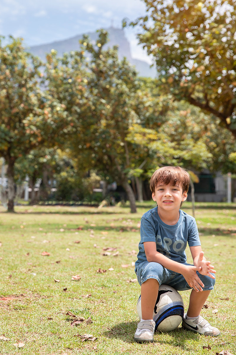 Irmão mais velho sentado sorrindo no ensaio de família ao ar livre

