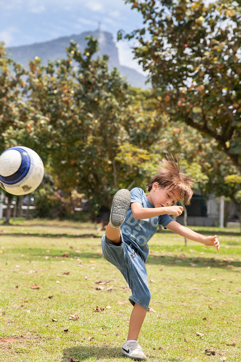Menino jogando bola no gramado durante ensaio de família na Lagoa