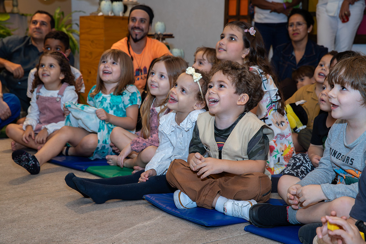 Grupo de crianças assistindo ao show com personagens no palco da festa

