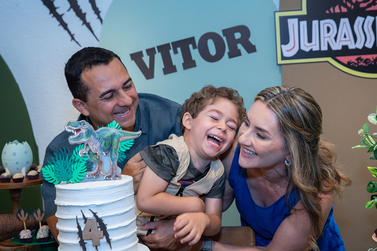 Pais com o aniversariante sorrindo na festa Jurassic Park no Espaço Aldeia

