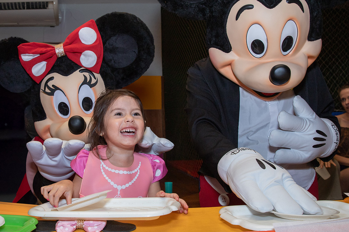 Menina sorrindo com fantasia da Minnie durante festa de aniversário temática