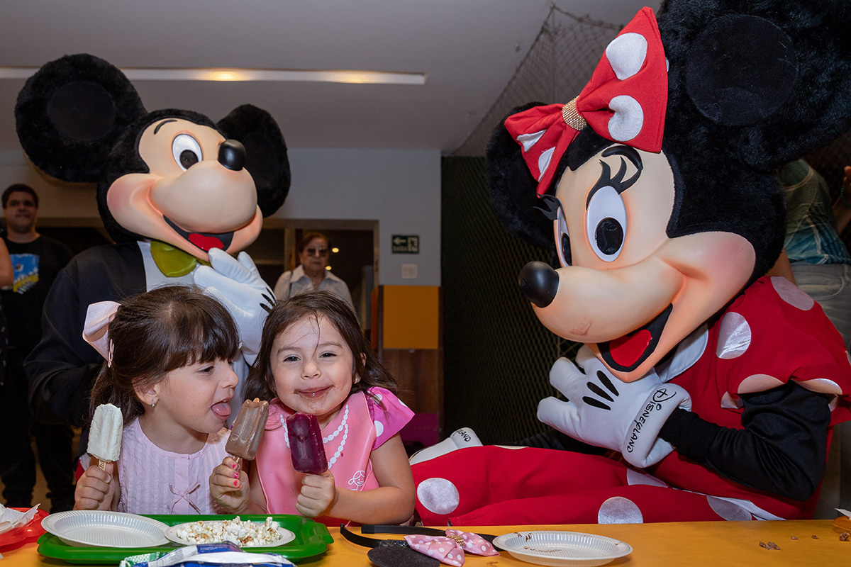 Aniversariante cercada pelos personagens vivos no salão da festa infantil