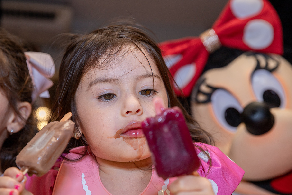 Aniversariante tomando picole no meio da diversão da festa temática
