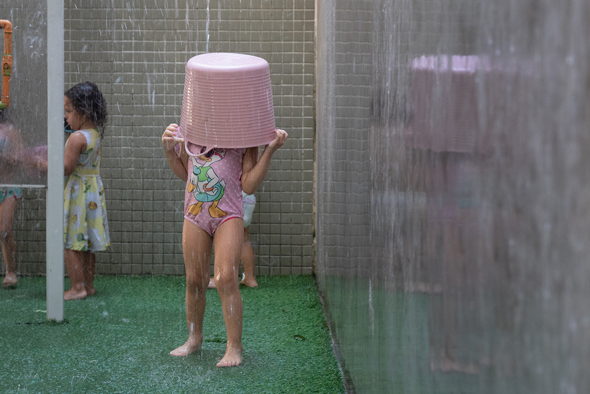 Criança saindo do circuito aquático com balde na cabeça em momento divertido
