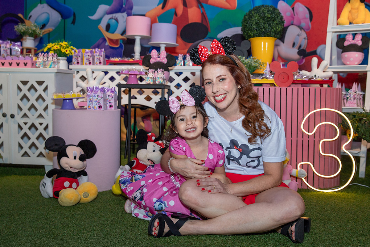 Mamãe abraçando a aniversariante com personagem da Arte de Contar ao fundo
