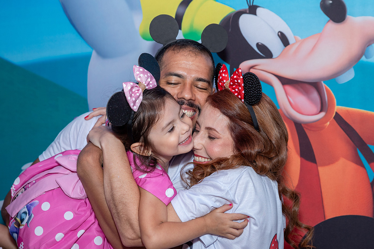 mae e pai abraçando aniversariante na festa infantil de tema Minnie