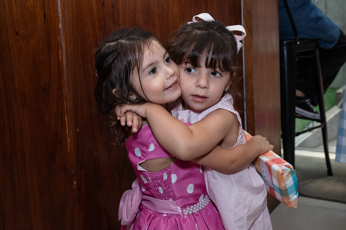 Amiguinha abraçando a aniversariante com carinho na festa temática da Minnie