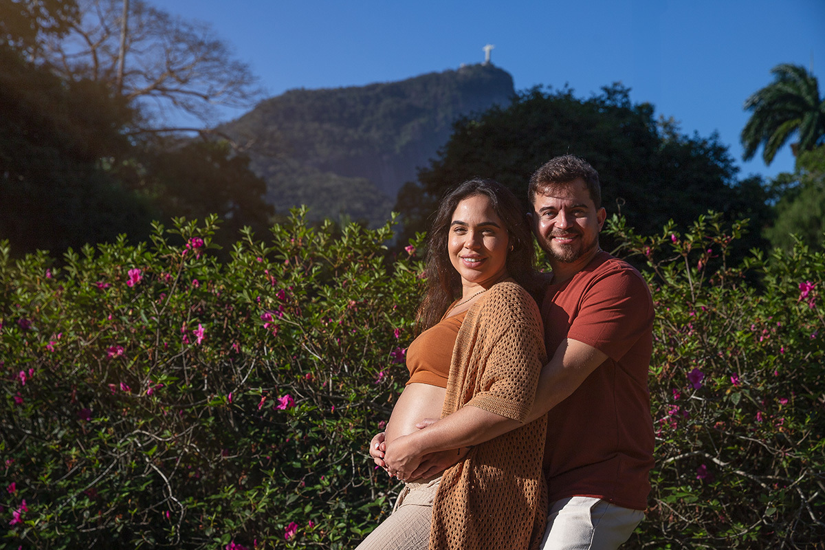casal se. abraçando durante ensaio gestante com o Corcovado ao fundo.