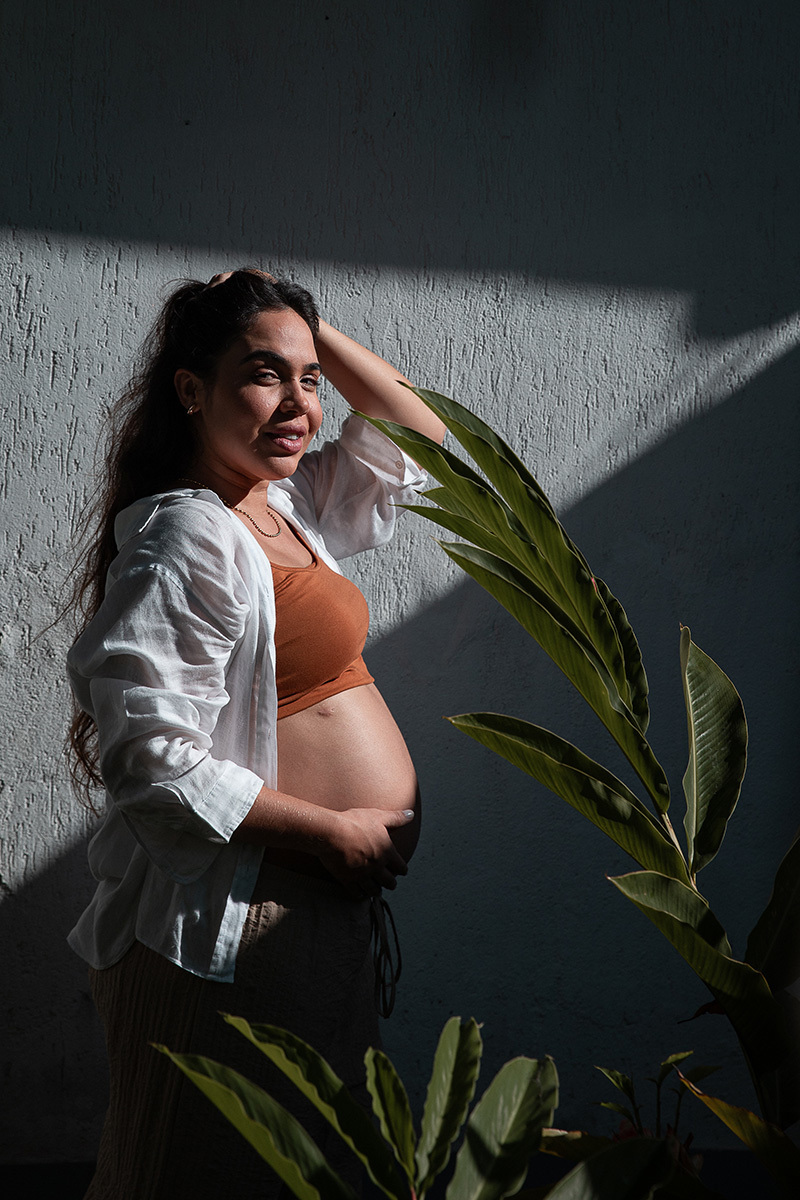 Gestante com a mão na cabeça e barriga durante ensaio de gestante