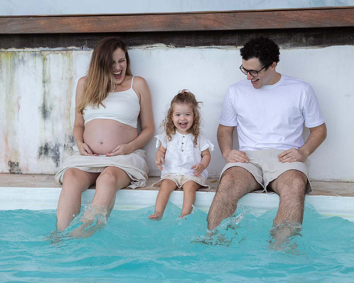 Família aproveitando um momento divertido na piscina durante o ensaio gestante.