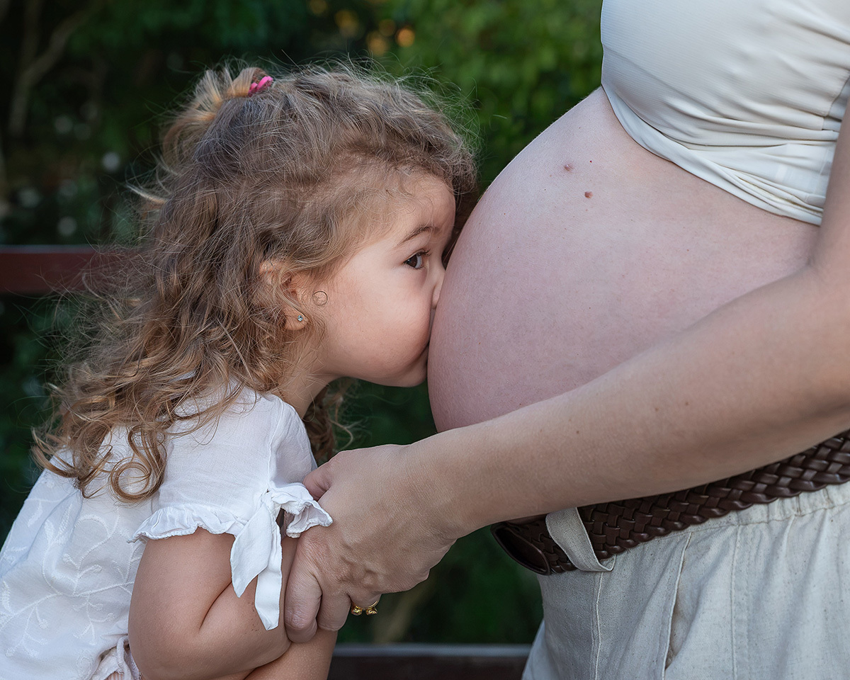 Sofia beija a barriga da mamãe demonstrando todo o amor pelo irmão Guilherme.
