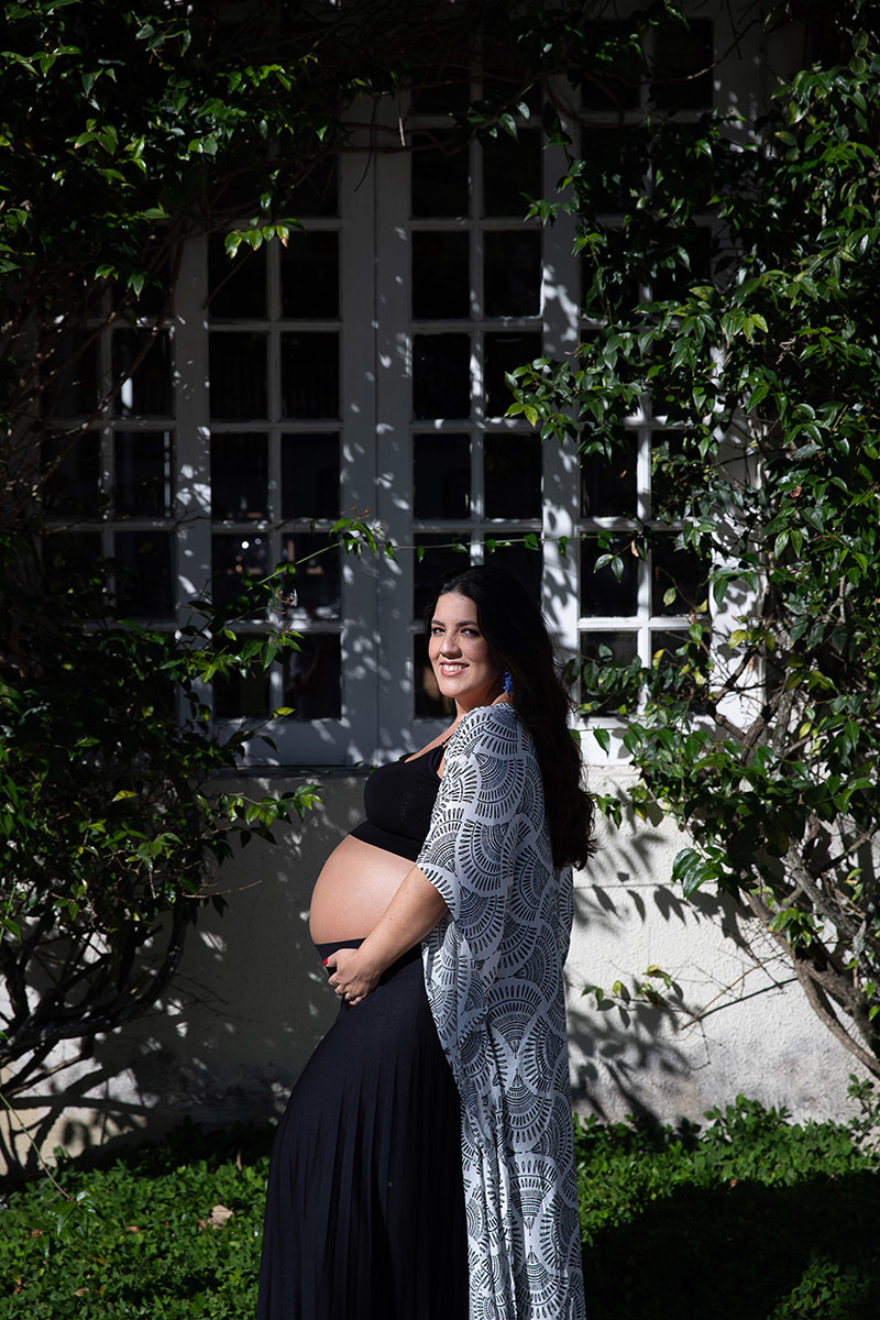 Retrato da gestante com luz natural  em frente a janela com plantas em ensaio gestante personalizado 
