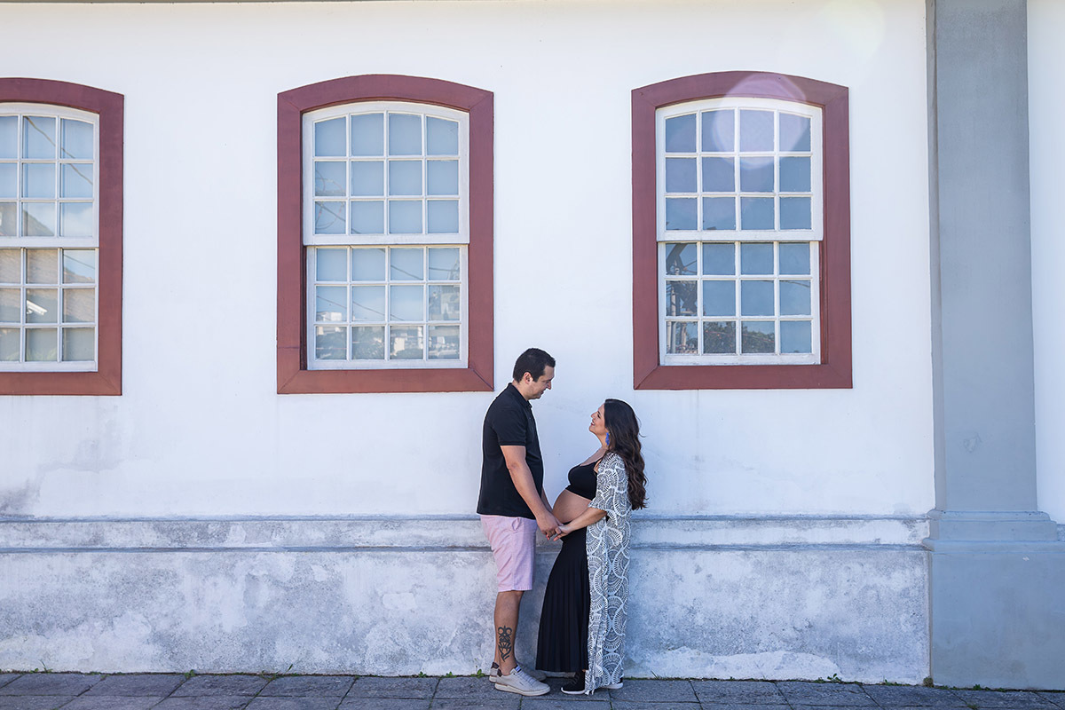 Casal em frente a prédio tradicional durante ensaio de gestante no Jardim Botânico do Rio de Janeiro