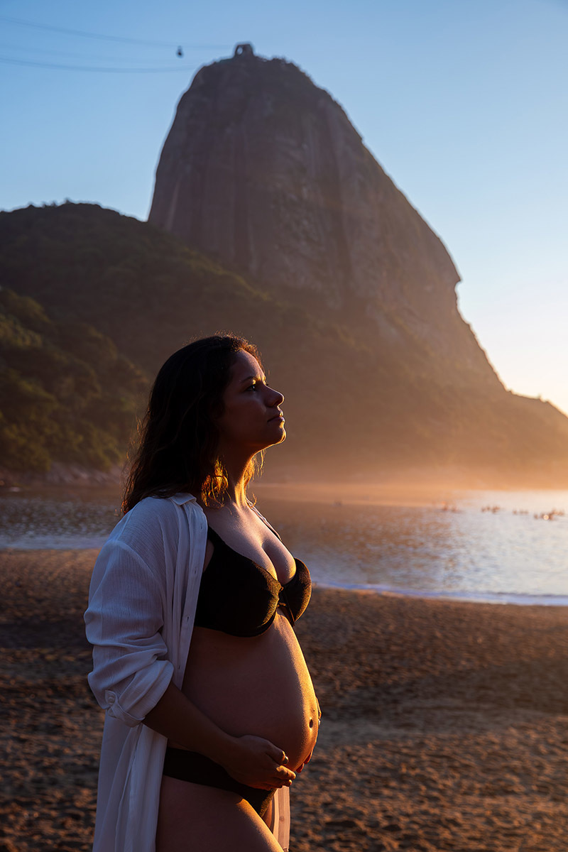 Gestante na Praia Vermelha com o morro da Urca ao fundo com luz dourada no nascer do sol