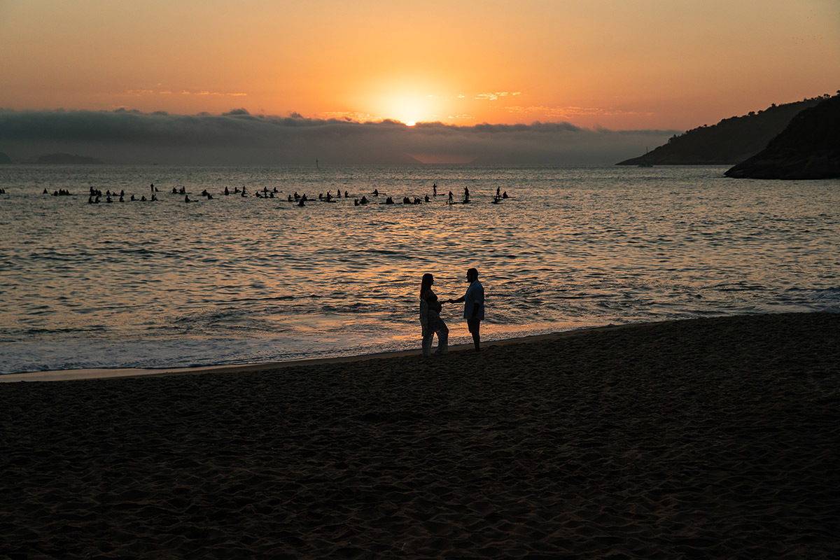 Silhueta de casal de gestante ao amanhecer na Praia Vermelha