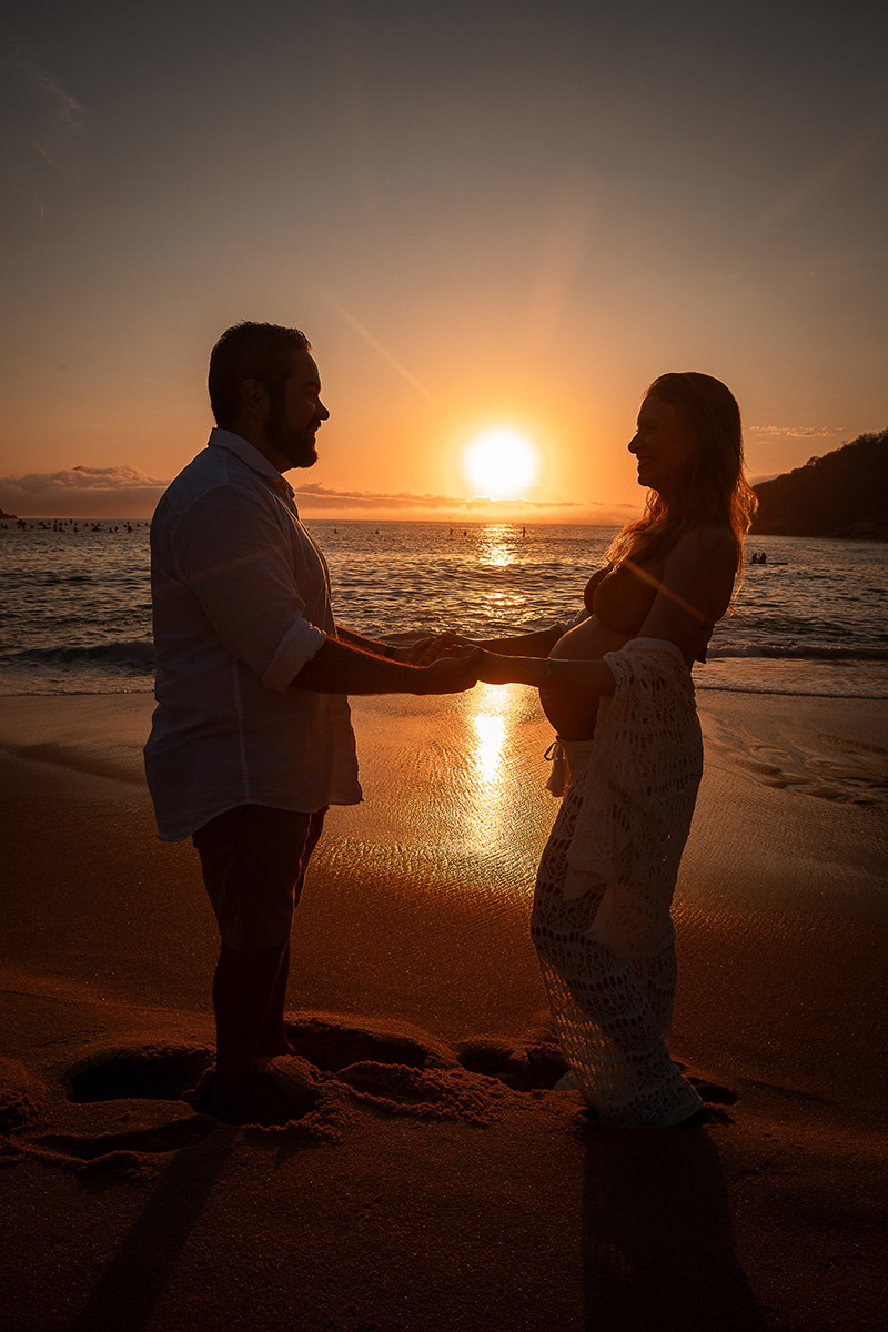 Casal formando a silhueta da barriga com sol nascente na Praia Vermelha.