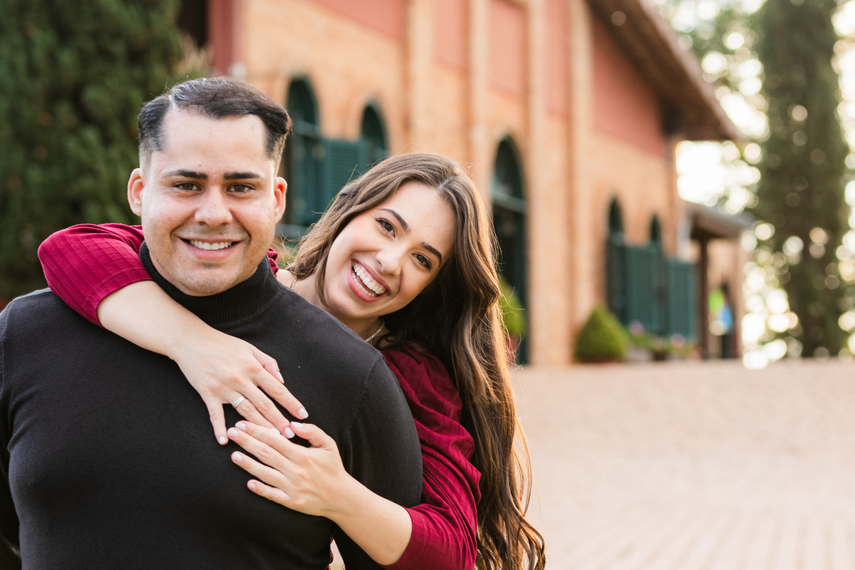 casal olhando para camera enquando a noiva fica de cavalinho nas costas do noivo