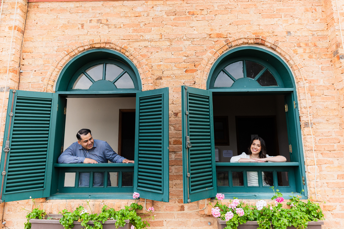 casal apoiado em janelas grandes verdes