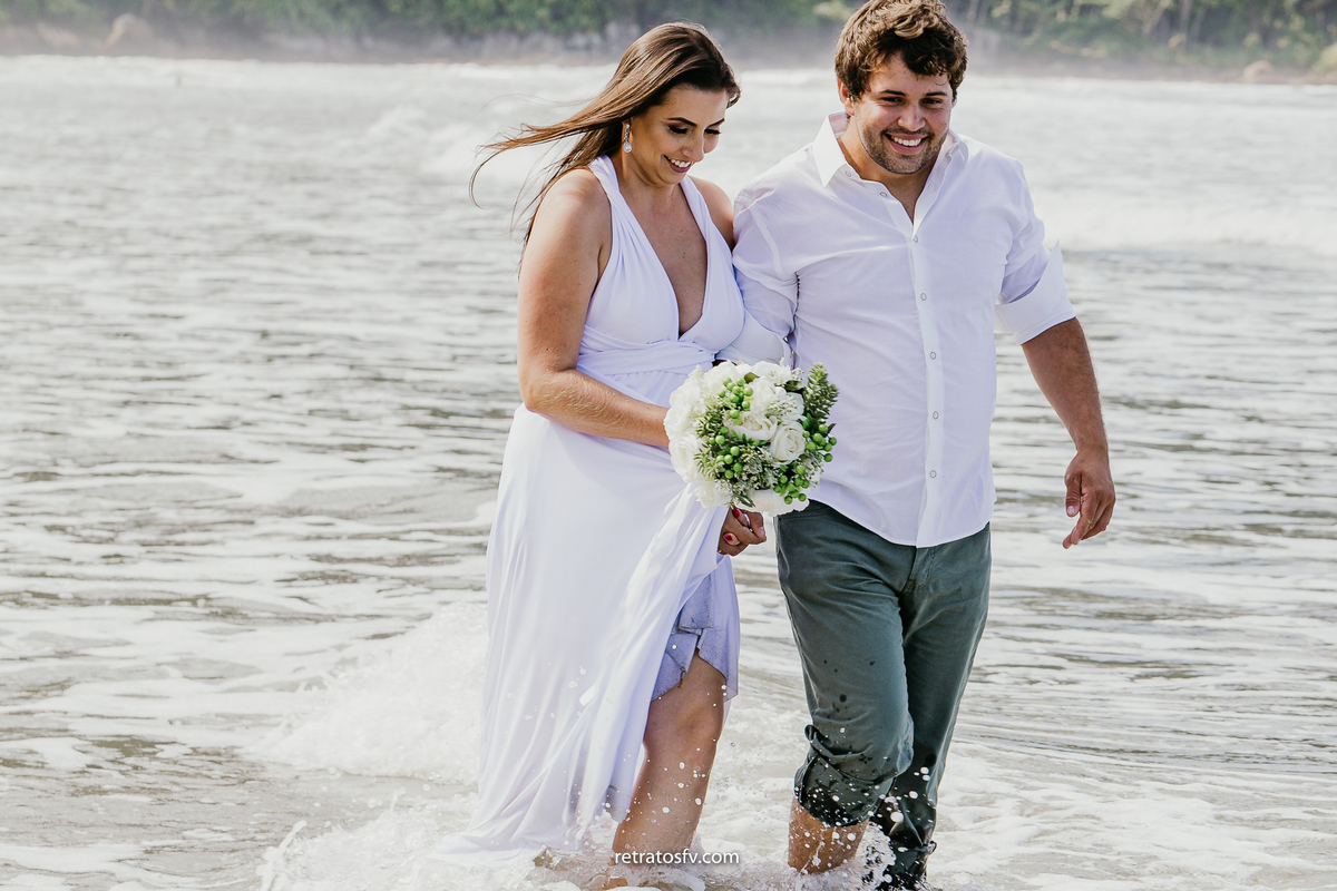 casal caminhando sobre a areia com a onda batendo no pés praia de iporanga