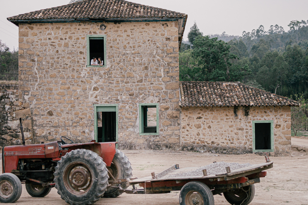 ensaio fotografico pre wedding casal  na janela no andar de cima da tulia com trator vermelho na frente