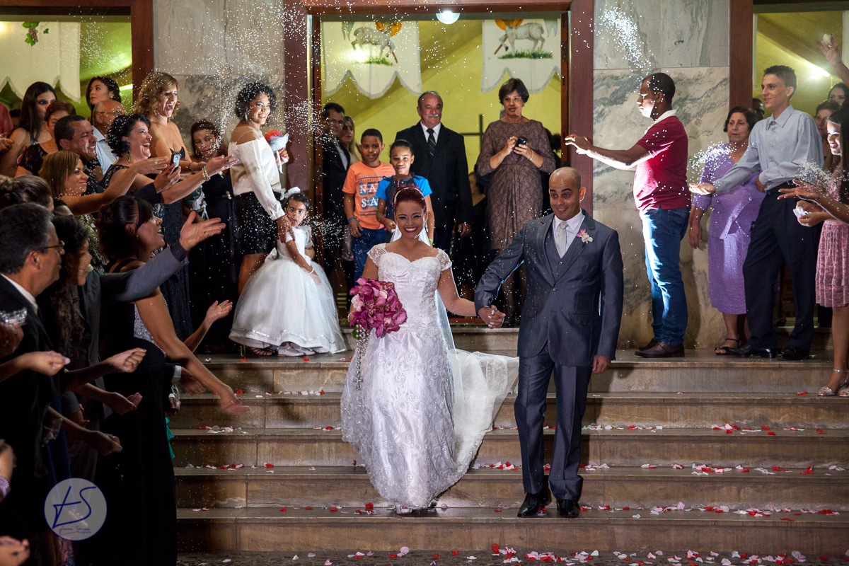 Na escadaria da igreja os recém casados levam um banho de chuva de arroz