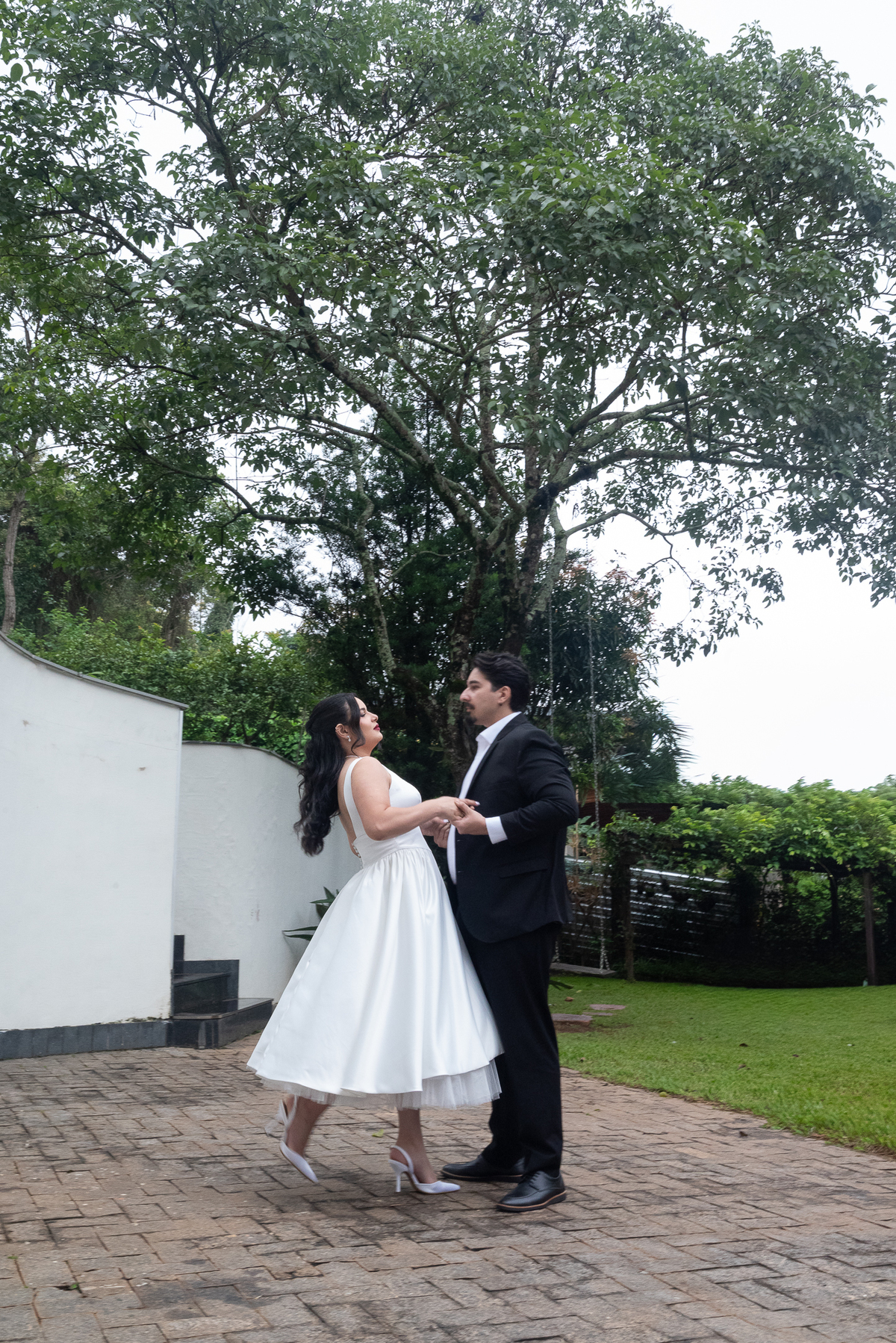 Ensaio fotográfico de casal na Casa Cenarium em Nova Lima MG, com Camila e Igor dançando ao ar livre em um cenário elegante e rodeado pela natureza.