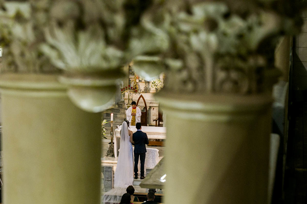 vista do casal de noivos por entre duas pilastras com detalhes barroco