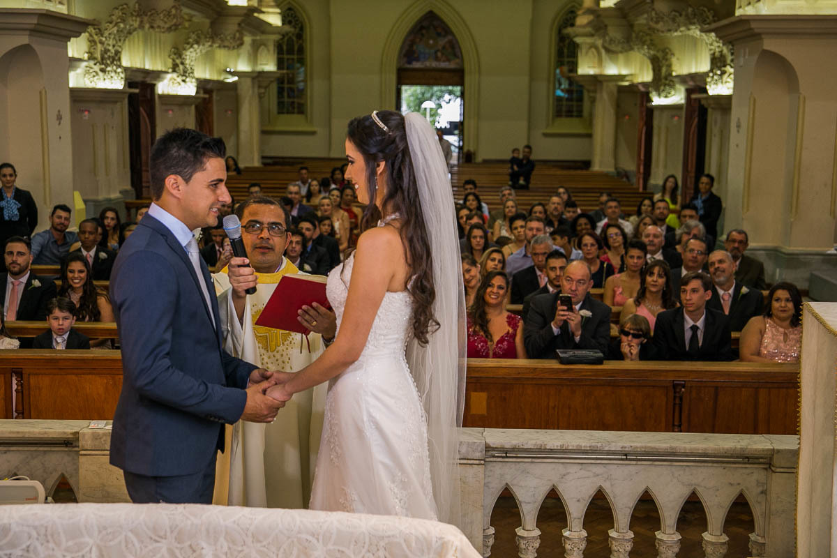 padre segurando o microfone para a o noivo na hora da jura do casamento