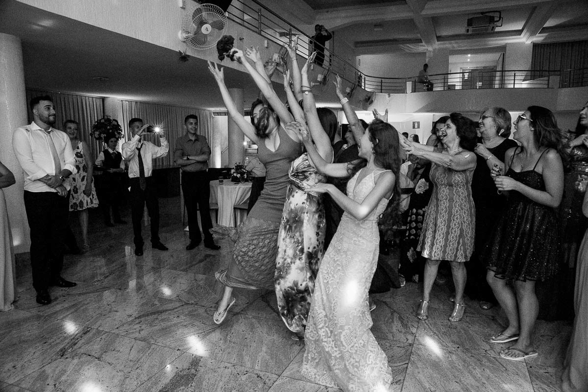 varias mulheres pulam tentando pegar o bouquet