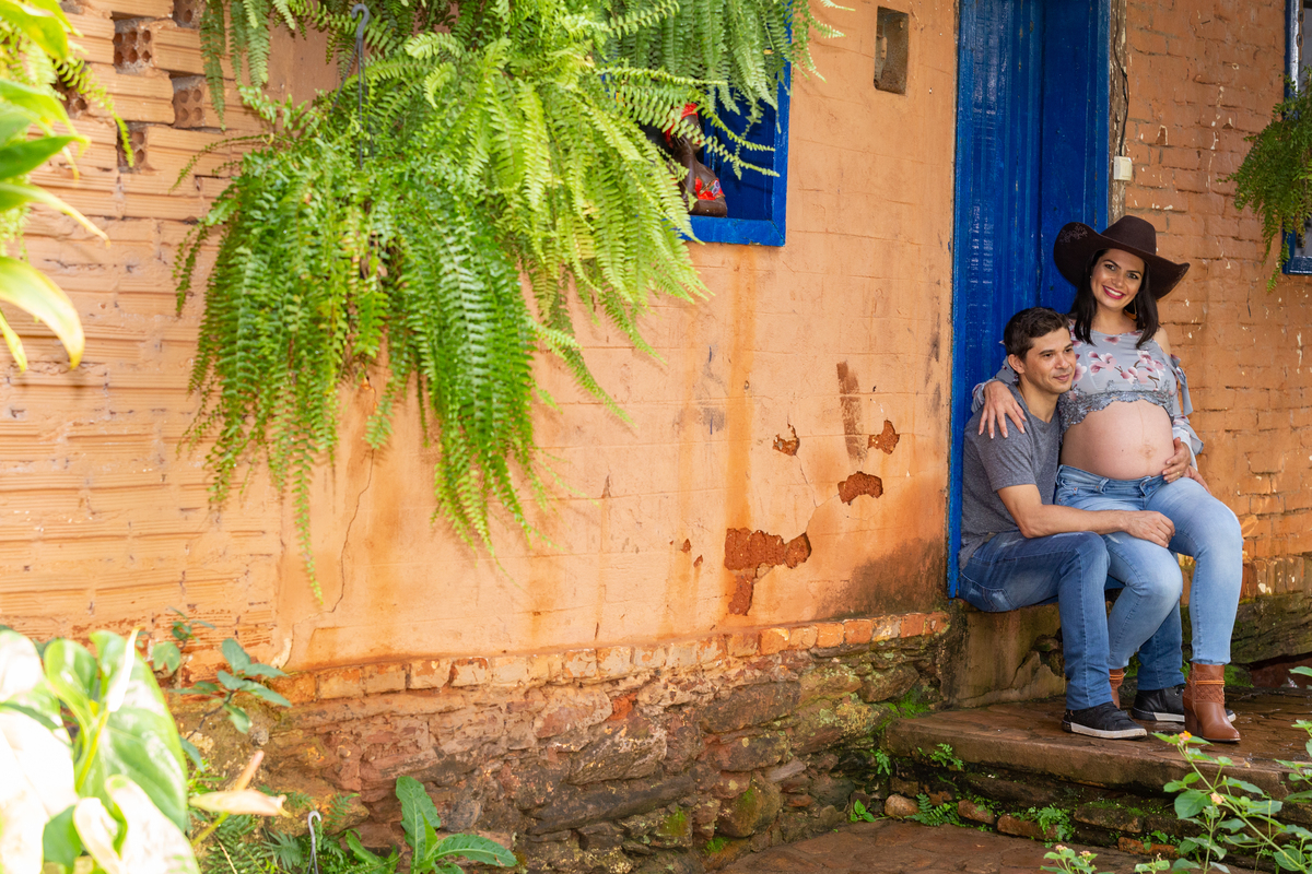 gestante sentada no colo do seu marido na porta de uma casinha de barro na fazenda arraial velho na foto de juca sousa