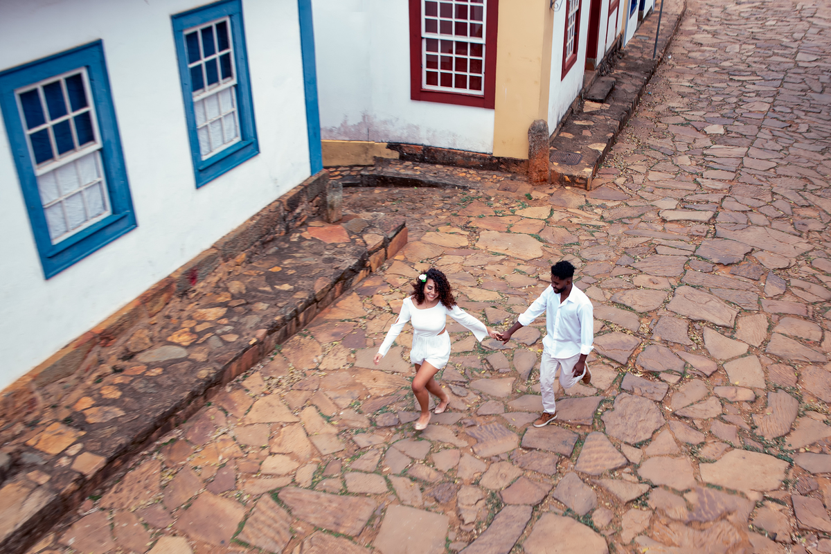 Casal correndo vestidos de branco em ensaio pré wedding Tiradentes Minas Gerais