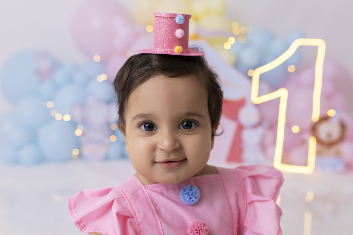 Bebê em ensaio Smash the Cake tema circo em estúdio fotográfico em Caraguatatuba, cenário colorido personalizado, bolo decorado, criança sorrindo e se divertindo durante sessão infantil