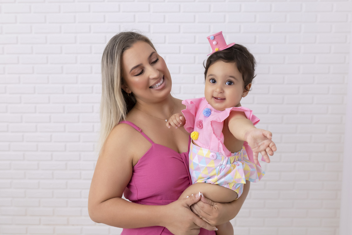 Bebê em ensaio Smash the Cake tema circo em estúdio fotográfico em Caraguatatuba, cenário colorido personalizado, bolo decorado, criança sorrindo e se divertindo durante sessão infantil