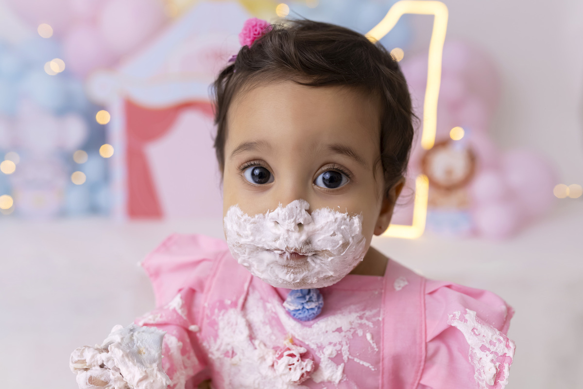 Bebê em ensaio Smash the Cake tema circo em estúdio fotográfico em Caraguatatuba, cenário colorido personalizado, bolo decorado, criança sorrindo e se divertindo durante sessão infantil