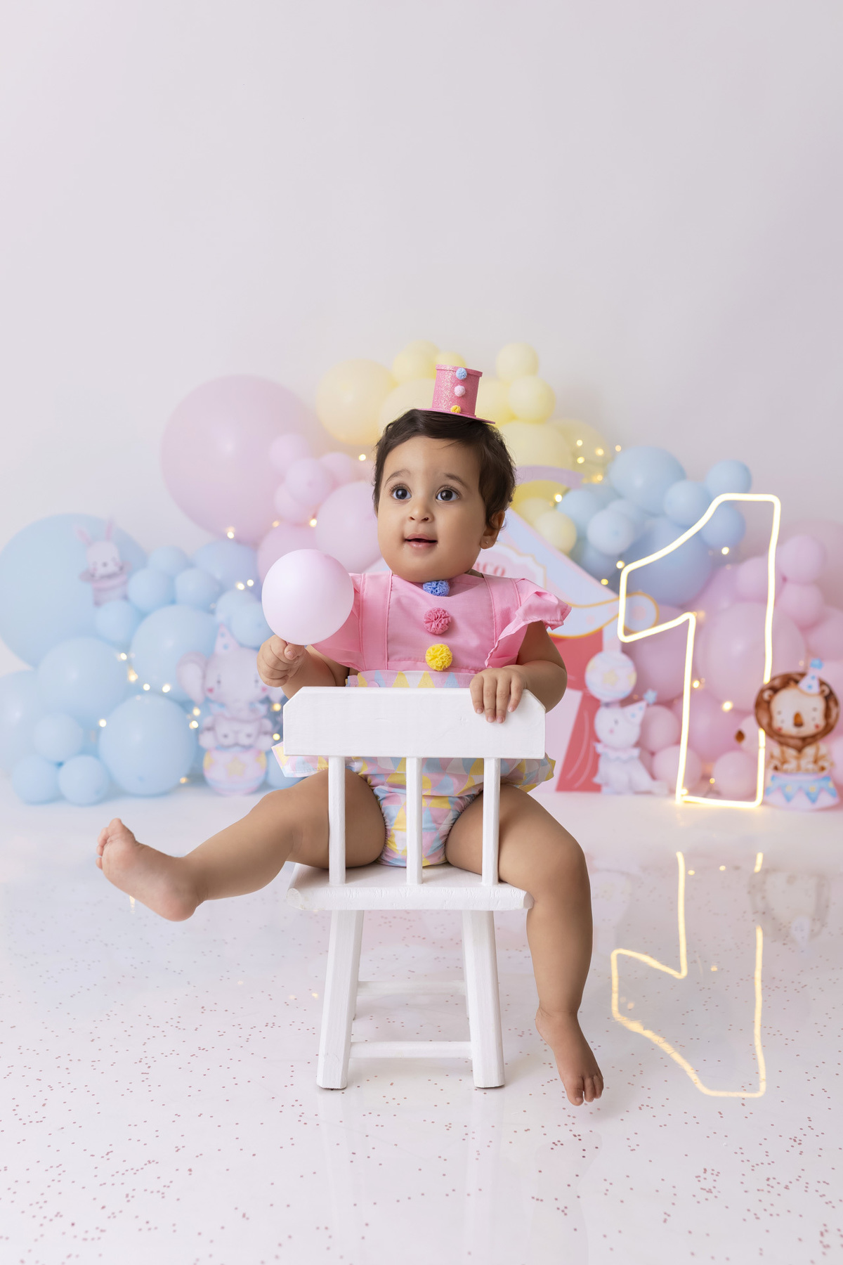 Bebê em ensaio Smash the Cake tema circo em estúdio fotográfico em Caraguatatuba, cenário colorido personalizado, bolo decorado, criança sorrindo e se divertindo durante sessão infantil