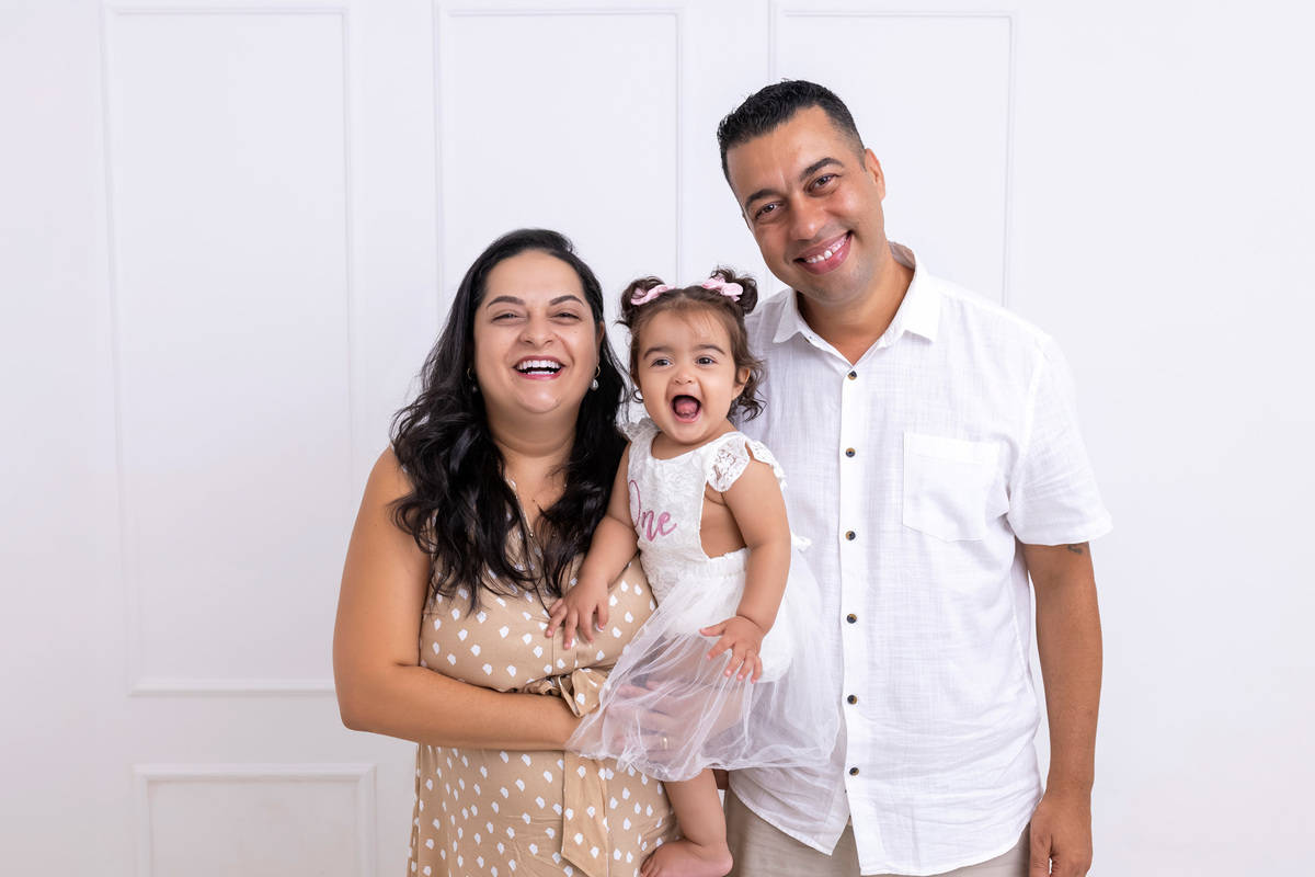Bebê em ensaio Smash the Cake colorido com flores e raposinha em estúdio em Caraguatatuba, cenário personalizado em tons de rosa e laranja, criança sorrindo e brincando com o bolo de aniversário