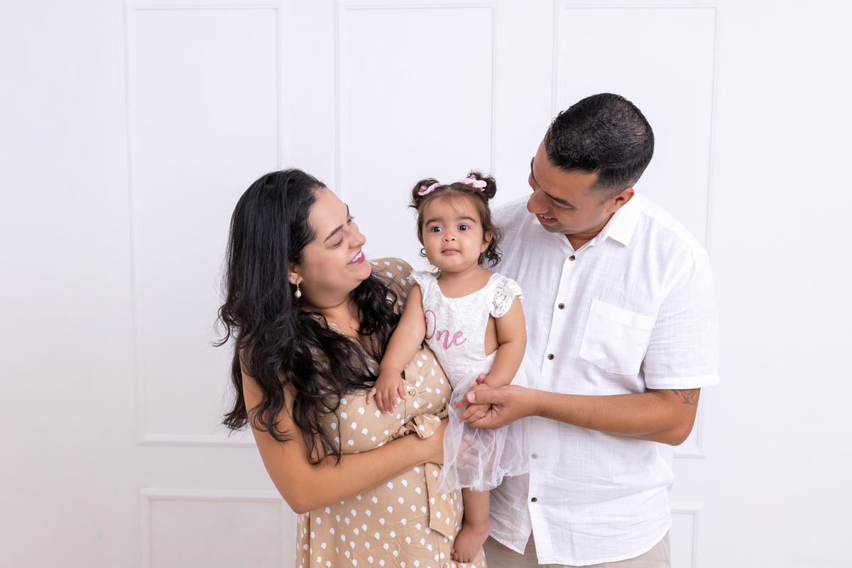 Bebê em ensaio Smash the Cake colorido com flores e raposinha em estúdio em Caraguatatuba, cenário personalizado em tons de rosa e laranja, criança sorrindo e brincando com o bolo de aniversário