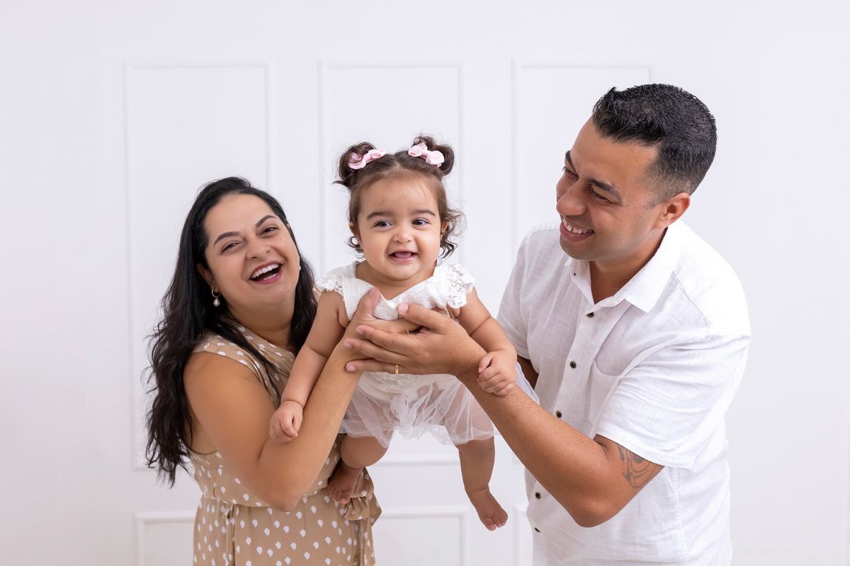 Bebê em ensaio Smash the Cake colorido com flores e raposinha em estúdio em Caraguatatuba, cenário personalizado em tons de rosa e laranja, criança sorrindo e brincando com o bolo de aniversário